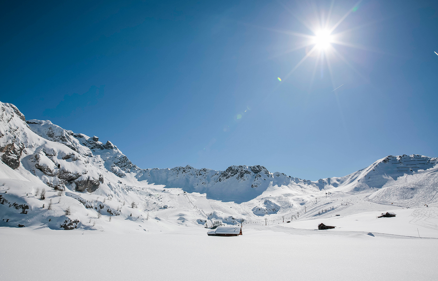 Panorama invernale soleggiato con piste innevate e cielo limpido