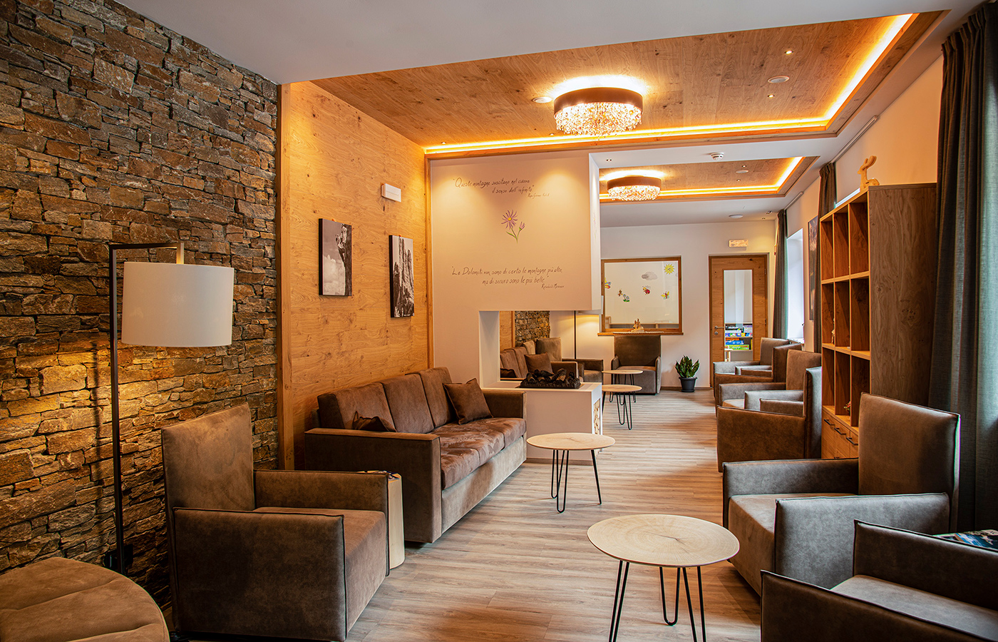 Accogliente hall con divani, poltrone e illuminazione calda in stile alpino.